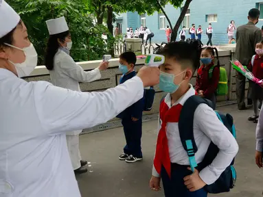 Siswa sekolah dasar Kim Song Ju diperiksa suhu tubuhnya sebelum memasuki sekolah di Pyongyang, Korea Utara, Rabu (3/6/2020). Korea Utara membuka kembali sekolah - sekolah di negara itu pada bulan ini setelah sebelumnya meliburkan karena kekhawatiran penyebaran virus corona. (AP/Jon Chol Jin)