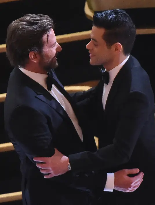 Aktor Bradley Cooper memberi ucapan selamat kepada Rami Malek sebelum menerima penghargaan di atas panggung Oscar 2019, Los Angeles, Minggu (24/2). Rami Malek menyabet Aktor Utama Terbaik di ajang Oscar untuk film Bohemian Rhapsody. (VALERIE MACON / AFP)