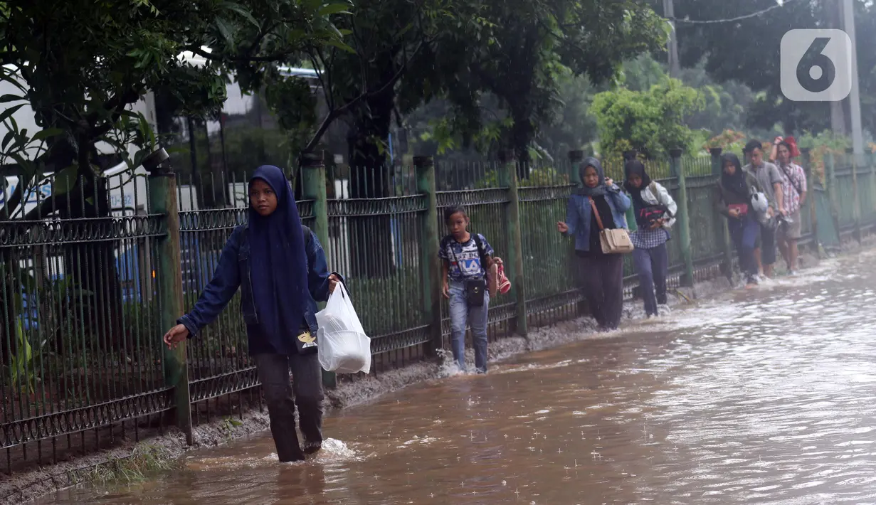 Warga melintasi Jalan Di Panjaitan dekat Halte Transjakarta Cawang Soetoyo yang banjir, Jakarta, Rabu (1/1/2020). Hujan yang mengguyur Jakarta sejak Selasa sore (31/12/2019) mengakibatkan banjir di sejumlah titik di Jakarta. (Liputan6.com/Helmi Fithriansyah)