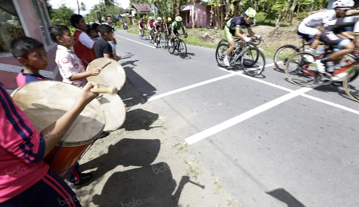 Anak-anak sekolah dasar Sikapak Barat, Pariaman Utara menabuh gendang menyambut pebalap pada etape ke-5 Tour de Singkarak dari Pantai Carocok-Painan menuju pantai Gondoriah-Pariaman, Sumatera Barart. (Bola.com/Nicklas Hanoatubun)