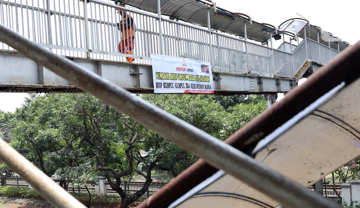 Pejalan kaki melintasi Jembatan Penyeberangan Orang (JPO) di Jalan Raya Lenteng Agung, Jakarta, Selasa (17/3/2020). Sebuah spanduk berisi ajakan menghindari kerumunan dan kumpul-kumpul untuk mencegah penyebaran virus Corona COVID-19 terpasang di JPO teresebut. (Liputan6.com/Helmi Fithriansyah)