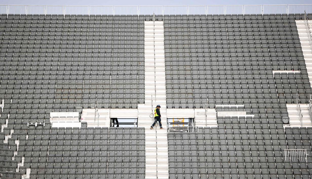 Diketahui, BMO Field merupakan stadion khusus sepak bola pertama di Kanada. Tampak dalam foto, para pekerja terlihat sedang merakit tempat duduk tribun sementara di BMO Field, Toronto, Kanada, pada Selasa 24 Maret 2026. (Cole BURSTON/AFP)