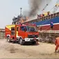 Petugas Damkar Bangkalan sedang berusaha memadamkan api di kapal cargo yang terbakar.