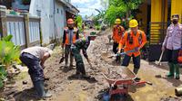 Petugas membersihkan lumpur sisa banjir di Jember. (Dian Kurniawan/Liputan6.com)
