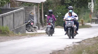Pengendara sepeda motor mengenakan masker saat melintas di Desa Pempatan, Karangasem, Bali, Sabtu (30/6). Pascaerupsi Gunung Agung, abu vulkanik masih menyelimuti kawasan tersebut. (Merdeka.com/Arie Basuki)