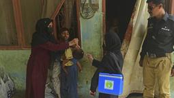 Petugas kesehatan memberikan vaksin polio kepada seorang anak selama kampanye vaksinasi polio dari pintu ke pintu di daerah kumuh di Karachi, Paksistan, Senin (23/5/2022). Pakistan meluncurkan upaya anti-polio baru pada hari Senin, lebih dari seminggu setelah pejabat mendeteksi kasus ketiga tahun ini di wilayah barat laut negara itu yang berbatasan dengan Afghanistan. (Asif HASSAN / AFP)