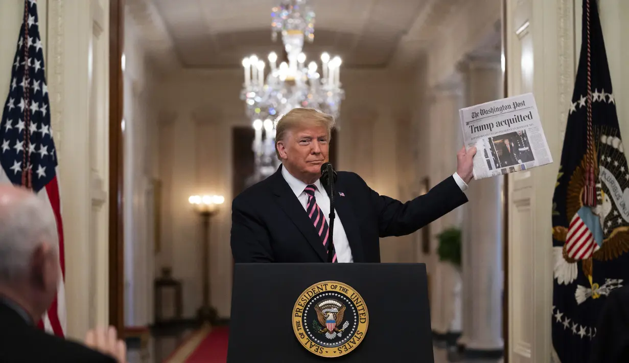 Presiden Donald Trump mengangkat sebuah surat kabar di hadapan awak media Ruang Timur Gedung Putih, Washington (6/2/2020). Surat kabar bertajuk utama tersebut bertuliskan "Trump dibebaskan". (AP Photo/Evan Vucci)