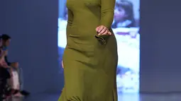 Model dengan kaki palsu melenggang di catwalk menampilkan koleksi Spring/Summer 2018 Teatum Jones selama London Fashion Week, 15 September 2017. Model tersebut memakai gaun panjang warna hijau lumut dan kaki palsu. (NIKLAS HALLE'N/AFP)