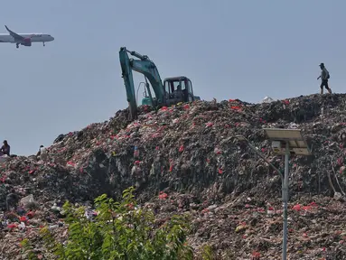 Sebuah pesawat melintas saat alat berat melakukan pengerukan sampah di TPA Rawa Kucing, Kota Tangerang, Banten, Rabu (27/9/2023). (Liputan6.com/Angga Yuniar)