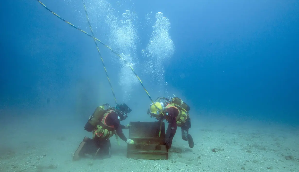 Penyelam mengambil botol anggur yang disimpan di dasar Laut Mediterania, Saint-Mandrier di Prancis, setelah percobaan penyimpanan satu tahun, 15 Mei 2017. Percobaan guna mengetahui dampak jika botol anggur itu disimpan lama di dalam air (Boris HORVAT/AFP)