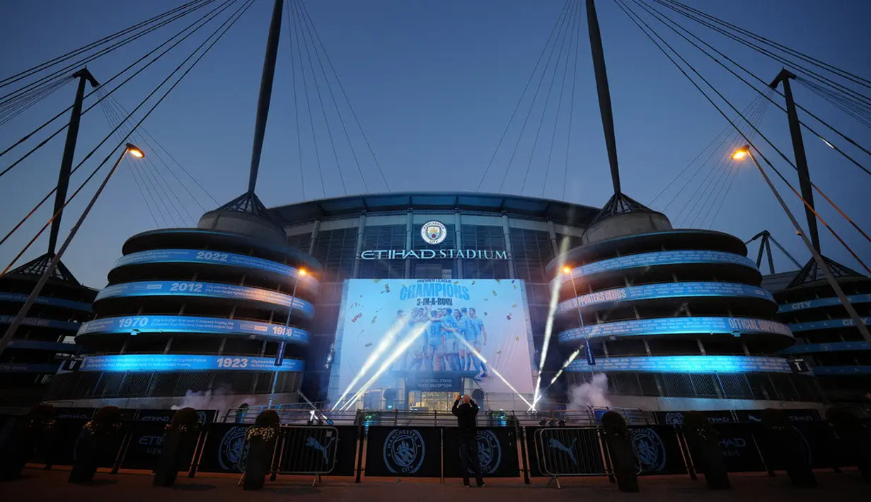 <p>Spanduk perayaan kemenangan Manchester City di Liga Inggris menerangi luar Etihad Stadium, Manchester, Inggris, Sabtu (20/5/2023). Manchester City meraih gelar juara Liga Inggris setelah penantang terdekat Arsenal kalah dari Nottingham Forest. (AP Photo/Jon Super)</p>