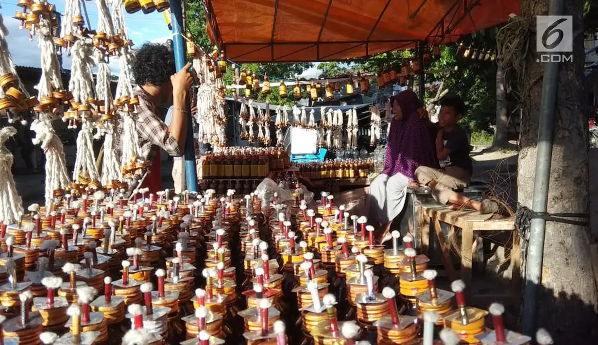 Pedagang menunggu pembeli saat berjualan pelita di Jalan Sam Ratulangi, Kota Gorontalo, Rabu (22/5/2019). Tumbilotohe atau malam pasang lampu yang digelar tiga hari menjelang Idul Fitri merupakan tradisi tua di Gorontalo. (Liputan6.com/Arfandi Ibrahim)