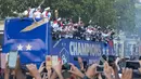Timnas Prancis mengikuti pawai dengan bus atap terbuka merayakan juara Piala Dunia 2018 di sepanjang Champs Elysees, Paris, Senin (16/7). Prancis menggelar pesta besar penyambutan sekaligus parade kemenangan bagi skuad ”Les Bleus”. (AP/Claude Paris)