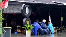 Sebagai upaya penanganan darurat, petugas Badan Penanggulangan Bencana Daerah (BPBD) bersama anggota TNI diterjunkan ke lokasi banjir. Tampak dalam foto, orang-orang duduk di sebuah kafe yang terendam banjir akibat hujan lebat di Legian Kuta, Denpasar, Bali, pada Selasa 24 Februari 2026. (SONNY TUMBELAKA/AFP)