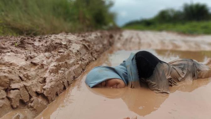 Warga Pulau Rimau Sumsel berendam di genangan lumpur di jalan Pulau Rimau Sumsel (Dok. Instagram @seputarpulaurimausumsel / Nefri Inge)