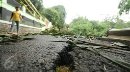 Kondisi sebagian aspal jalan Gardu, Jagakarsa yang mengalami longsor pada Jumat (12/2) lalu, Jakarta, Sabtu (13/2/2016). Longsor terjadi akibat guyuran hujan deras dan tidak ada korban dalam peristiwa ini. (Liputan6.com/Helmi Fithriansyah)