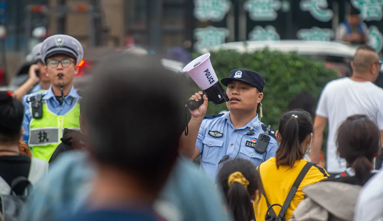 Polisi memandu pengunjung yang datang untuk menyaksikan gelombang pasang Sungai Qiantang di Hangzhou, Zhejiang, China, 4 Oktober 2020. Gelombang pasang Sungai Qiantang terjadi bertepatan dengan libur Hari Nasional dan Festival Pertengahan Musim Gugur tahun ini. (Xinhua/Jiang Han)