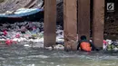 Aksi petugas PPSU bersihkan sampah yang tersangkut ditengah deras arus aliran anak kali Ciliwung, Jakarta, Senin (22/7/2019). Pembersihan sungai dari berbagai sampah tersebut dimaksudkan agar tidak ada penumpukan sampah dan sedimentasi saluran di sepanjang sungai. (Liputan6.com/Faizal Fanani)