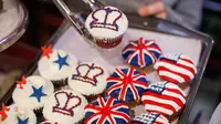 Karyawan memperlihatkan cupcakes edisi khusus untuk menghormati pernikahan Pangeran Harry dan Meghan Markle di Hummingbird Bakery, London, 11 Mei 2018. Pernikahan Harry dan Meghan digelar 19 Mei esok di Kapel St. George, Istana Windsor. (AFP/Tolga AKMEN)