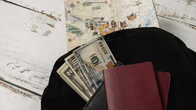 Dompet, paspor, sejumlah uang, dan peta dunia di atas sebuah meja (Foto Dok: Freepik/freepik)