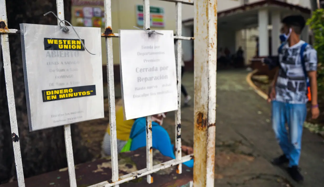 Seorang pria berjalan dekat pemberitahuan penutupan kantor Western Union di Havana, Kuba, Senin (23/11/2020). Layanan transfer uang terkemuka di dunia itu menutup lebih dari 400 gerainya di Kuba menyusul sanksi ekonomi terbaru yang dikeluarkan Amerika Serikat terhadap negara itu. (Yamil LAGE/AFP)