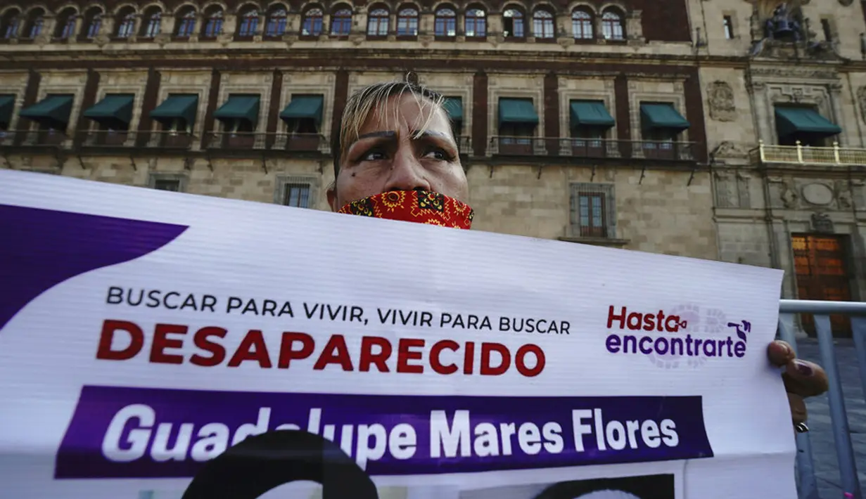 Maria de la Luz Flores memegang poster putrinya Guadalupe Morales Flores yang hilang pada 7 September 2020 dan ditemukan 29 Maret 2021 saat protes di luar Istana Nasional menuntut jawaban dari pemerintah tentang orang-orang hilang di Mexico City, Meksiko, 13 Desember 2021. (AP Photo/Marco Ugarte)