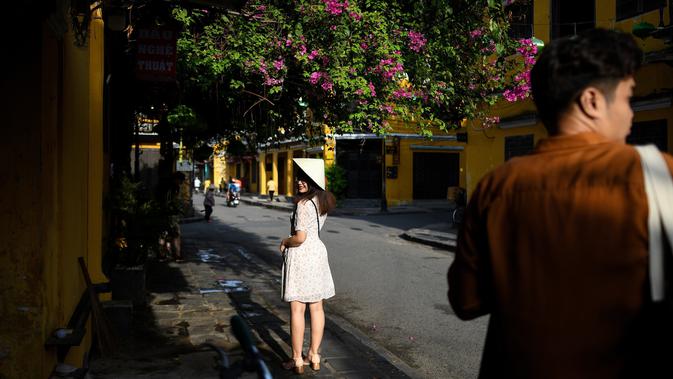 Gambar pada 14 September 2019 memperlihatkan seorang turis berpose di kota tua Hoi An, Vietnam. Kota Tua Hoi An merupakan destinasi wisata yang cukup populer di Vietnam, didukung oleh statusnya sebagai salah satu Unesco World Heritage Site. (Manan VATSYAYANA/AFP)