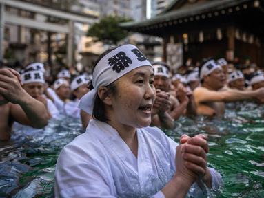 Penganut Shinto mandi dengan air dingin di Kuil Teppozu Inari, Tokyo, Jepang, 8 Januari 2023. Ritual Tahun Baru ini dilakukan untuk memurnikan jiwa dan raga. (Philip FONG/AFP)