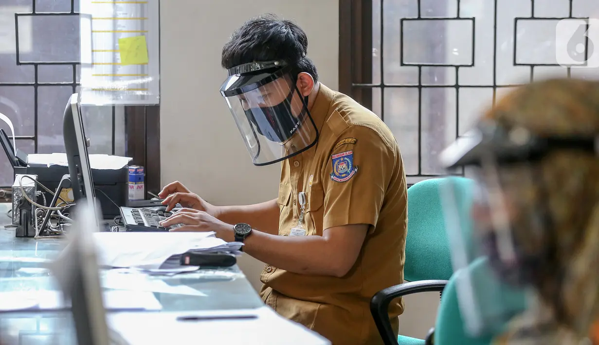 Petugas loket lengkap dengan masker dan face shield sedang mengetik saat proses pembuatan KTP Elektronik di Kecamatan Pamulang, Tangerang Selatan, Senin (15/6/2020). Dukcapil Tangsel membuka layanan rekaman E-KTP jelang Pilkada dengan menerapkan ketentuan New Normal. (Liputan6.com/Fery Pradolo)