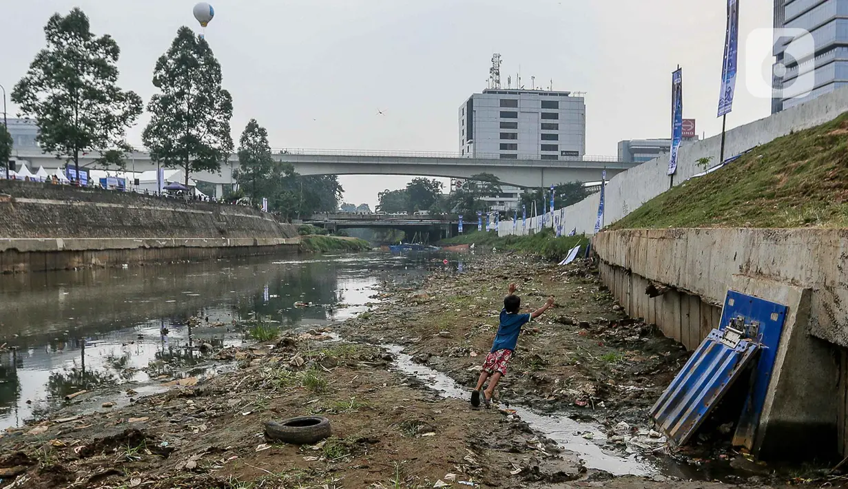Seorang anak bermain di aliran sungai ciliwung yang mengering di kawasan MT Haryono, Jakarta, Kamis (27/7/2023). (Liputan6.com/Faizal Fanani)