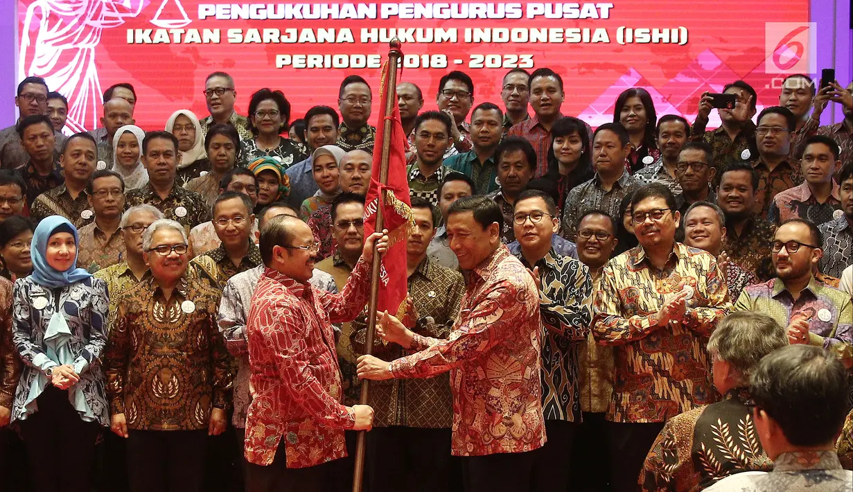 Menko Polhukam Wiranto memberikan bendera ke Ketua Umum Ikatan Sarjana Hukum Indonesia (ISHI) Amzulian Rifai saat pelantikan di Kemenkumham, Jakarta, Senin (30/7). Acara ini dalam rangka Pengukuhan PP ISHI 2018-2023. (Liputan6.com/Herman Zakharia)