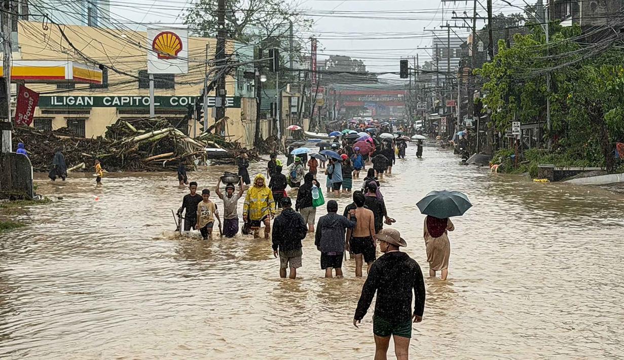 Badai Tropis Penha memicu banjir besar dan kerusakan di wilayah Iligan City, Lanao del Norte, pada Jumat 6 Februari 2026. Meski arah badai sempat bergeser, hujan lebat yang terus-menerus tetap mengakibatkan banjir di berbagai titik di kota tersebut. Tampak dalam foto, warga berjalan menerobos genangan air yang dibawa oleh Badai Tropis Penha di Iligan, provinsi Lanao del Norte, Filipina, pada Jumat 6 Februari 2026. (Merlyn Manos/AFP)