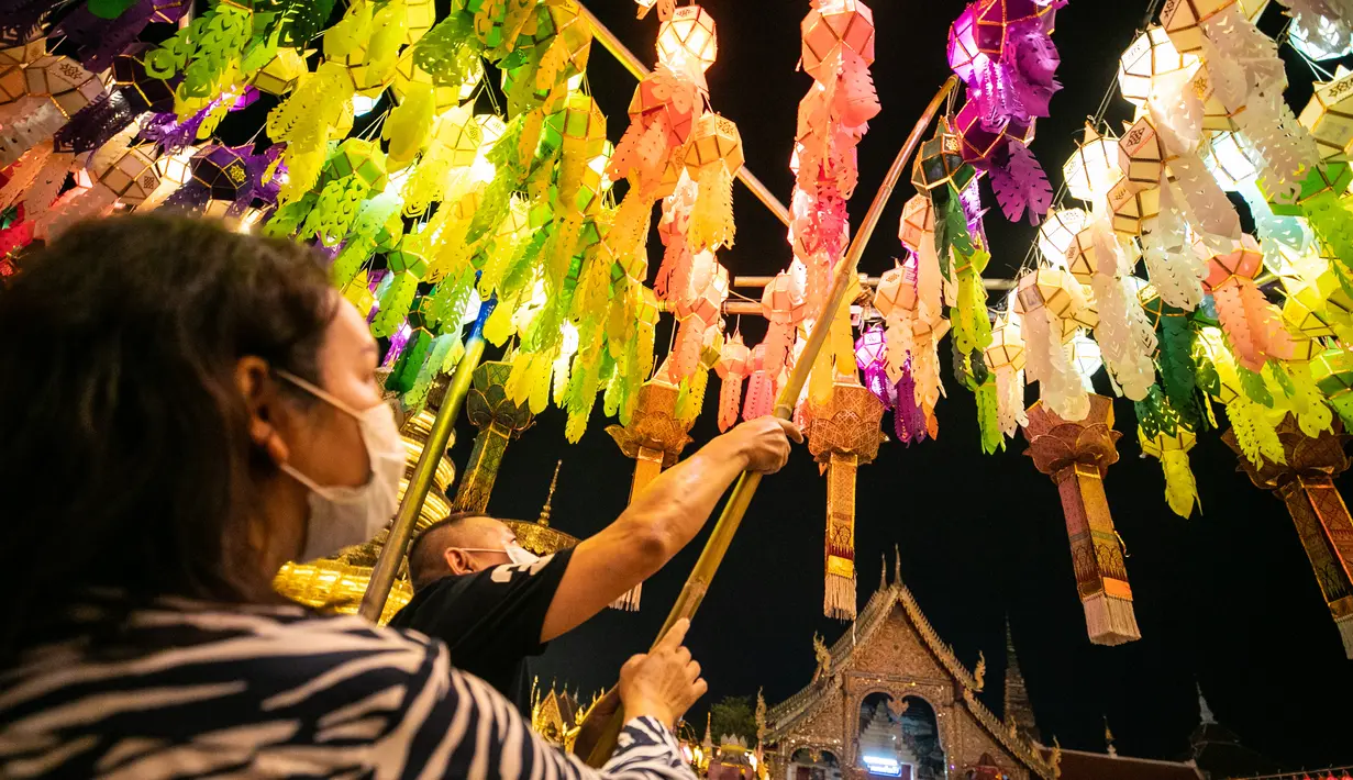Orang-orang menggantung lampion di Wat Phra That Hariphunchai, Lamphun, Thailand, 1 November 2020. Sekitar 100.000 lampion digantung di Wat Phra That Hariphunchai sebagai bagian dari perayaan festival tradisional Yi Peng. (Xinhua/Zhang Keren)