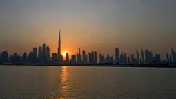 Matahari terbenam di belakang bangunan tertinggi di dunia Burj Khalifa dan gedung-gedung bertingkat lainnya, di Dubai, Uni Emirat Arab pada Sabtu (12/9/2020). (Photo by Karim SAHIB / AFP)