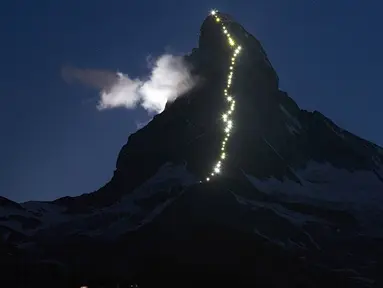 Deretan cahaya memanjang, terlihat di punggung gunung Matterhorn, Zermatt, Swiss, Senin (13/7/2015). Lampu tersebut dipasang merayakan keberhasilan Briton Edward Whymper, menaklukan puncak gunung Matterhorn pada 14 Juli 1865. (REUTERS/Denis Balibouse)