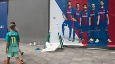 Seorang anak mengenakan jersey Neymar melewati sebuah poster baru yang dipasang di luar Stadion Camp Nou di Barcelona (2/8). Sebelumnya, poster tersebut menampilkan pemain depan Barcelona Neymar dari Brasil. (AFP Photo/Josep Lago)