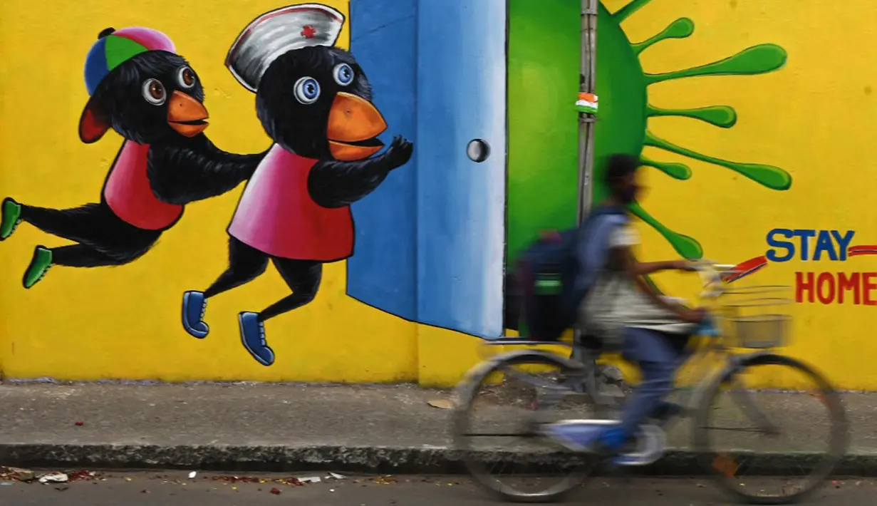 Seorang pria mengendarai sepeda melewati mural kesadaran virus corona COVID-19 di sepanjang pinggir jalan di Chennai, India, 13 September 2021. India bersiap hadapi kemungkinan lonjakan kasus COVID-19 sekitar musim festival September hingga November. (ARUN SANKAR/AFP)