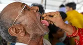 Seorang pasien menelan ikan murrel hidup dengan ramuan obat asma yang diberikan oleh keluarga Bathini Goud, di tempat pameran di Hyderabad, India, Jumat (9/6/2023). (Photo by Noah SEELAM / AFP)