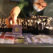 Pegawai menunjukkan emas batangan 24 karat di gerai Galeri 24, kawasan Kebayoran Baru, Jakarta, Kamis (5/8/2021). Untuk buyback atau pembelian kembali, harga emas Antam mencatatkan penurunan Rp 2.000 per gram menjadi Rp 834 ribu per gram pada Kamis (5/8). (Liputan6.com/Angga Yuniar)