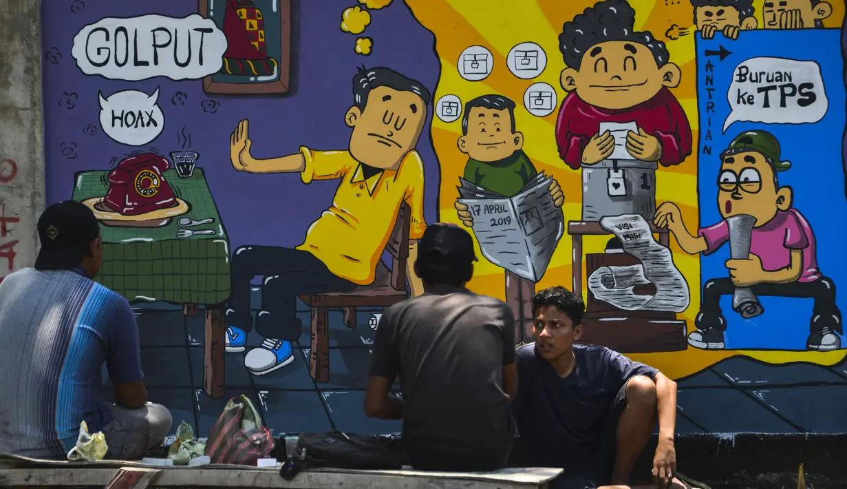 Sejumlah pria duduk di depan mural Pemilu 2019 di Banda Aceh, provinsi Aceh (17/3). Indonesia akan mengadakan pemilihan presiden dan parlemen secara serentak pada 17 April. (AFP Photo/Chaideer Mahyuddin)
