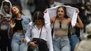 Penonton berjalan di tengah hujan pada hari pertama turnamen tenis Australia Terbuka di Melbourne, Senin (20/1/2020). Pertandingan Roger Federer melawan Steve Johnson sempat terhenti akibat hujan deras yang mengguyur Rod Laver Arena.  (AFP Photo/Greg Wood)