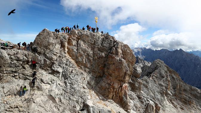 Orang-orang mengantre untuk mencapai puncak salib di puncak gunung tertinggi Jerman, Zugspitze, dekat Garmisch-Partenkirchen, Jerman pada 19 Agustus 2020. Setiap tahunnya gunung dengan ketinggian 2.962 meter tersebut membuat sekitar setengah juta pengunjung terpesona. (AP Photo/Matthias Schrader)