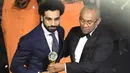 Mohamed Salah menerima trofi Pemain Terbaik Afrika 2017 dari Presiden CAF, Ahmad Ahmad (kanan) pada ajang The African Footballer of the Year Award  di Accra International, Accra, (4/1/2018). Salah mengalahkan Sadio Mane. (AFP/Pius Utomi Ekpei)