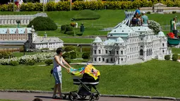 Pengunjung sambil mendorong kereta bayi melihat miniatur Wina Belvedere Palace di Taman Minimundus, Klagenfurt, Austria, Senin (8/8). Sekitar 150 model bangunan unik dari berbagai belahan dunia dipamerkan di Taman Minimundus. (REUTERS / Heinz-Peter Bader)