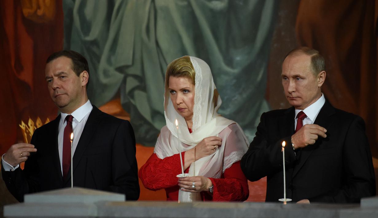 Presiden Rusia Vladimir Putin (kanan) bersama Perdana Menteri Rusia Dmitry Medvedev (kiri) dan istrinya Svetlana saat menjalani prosesi Paskah Ortodoks di Gereja Katedral Kristus Juru Selamat di Moskow, Rusia,(16/4). (AFP Photo / Vasily Maximov)