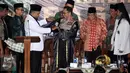 Sekjen Pagar Nusa M Nabil Haroen memberikan jubah kehormatan pencak silat Nahdlatul Ulama (PSNU) Pagar Nusa kepada Kapolri Jendral Tito Karnavian pada acara pembukaan Kongres III PSNU di TMII, Jakarta, Rabu (3/5). (Liputan6.com/Johan Tallo)