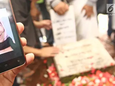 Keluarga menunjukkan foto Laila Sari saat dimakamkan di Tempat Pemakaman Umum (TPU) Karet Bivak, Jakarta, Selasa (21/11). Laila Sari meninggal dunia saat pulang syuting, di usai 82 tahun. (Liputan6.com/Herman Zakharia)