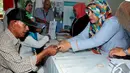 Seorang petugas memberikan warga Kartu Indonesia Sehat saat peluncuran perdana di Kantor Pos Fatmawati, Jakarta, Senin (3/11/2014). (Liputan6.com/Johan Tallo)