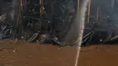 Petugas pemadam berupaya menyemprotkan air saat terjadinya kebakaran yang melanda rumah hunian semi permanen di bantaran sungai anak kali ciliwung, Kawasan Kampung Berland, Jakarta, Rabu (2/9/2015). (Liputan6.com/Johan Tallo)
