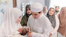 Alvin Faiz tampak berhati-hati saat mencukur rambut Mikail sebagai momen simbolis. Raut bahagia mereka begitu terpancar saat menggelar acara akikah. Tampak pula keluarga dan orang-orang terdekat hadir di acara tersebut. (Liputan6.com/IG/@malycaphoto)